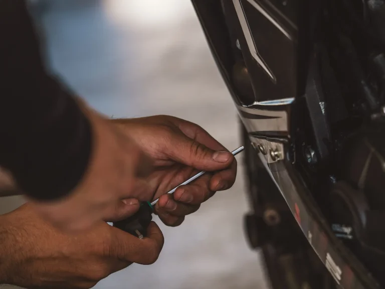 handen die een stuk motorkuip vastschroeven, onderhoud motor zelf doen, zelf motor onderhouden.