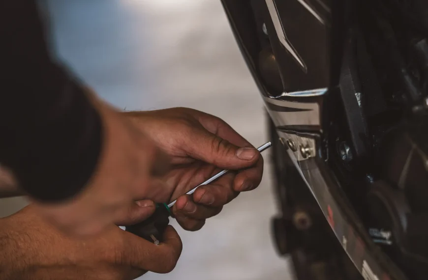 handen die een stuk motorkuip vastschroeven, onderhoud motor zelf doen, zelf motor onderhouden.